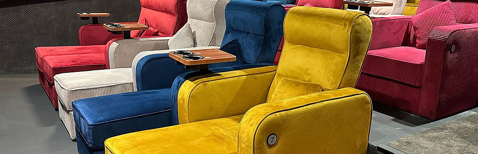 אולם Cinema Lounge: מיטות זוגיות וכורסאות נפתחות בצבעים צהוב, כחול, אדום ולבן, עם שולחנות צד קטנים